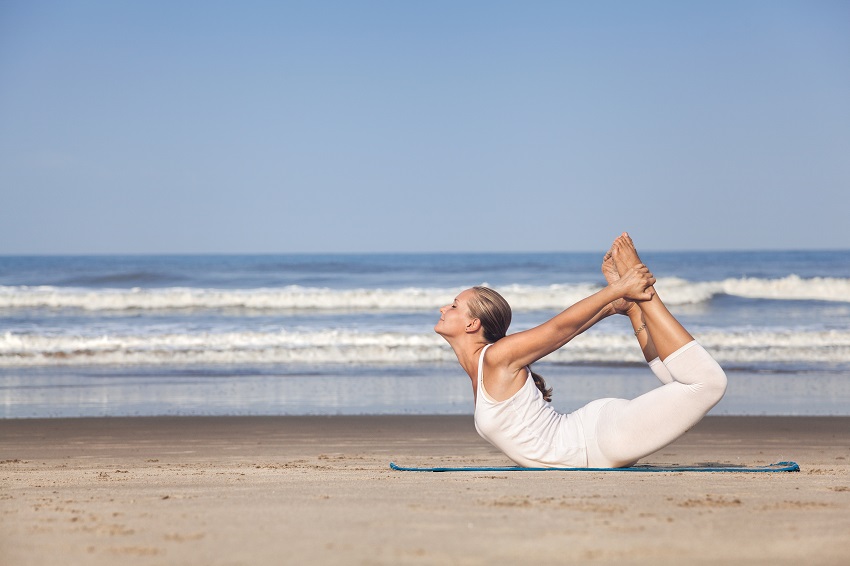 bow yoga pose on the beach